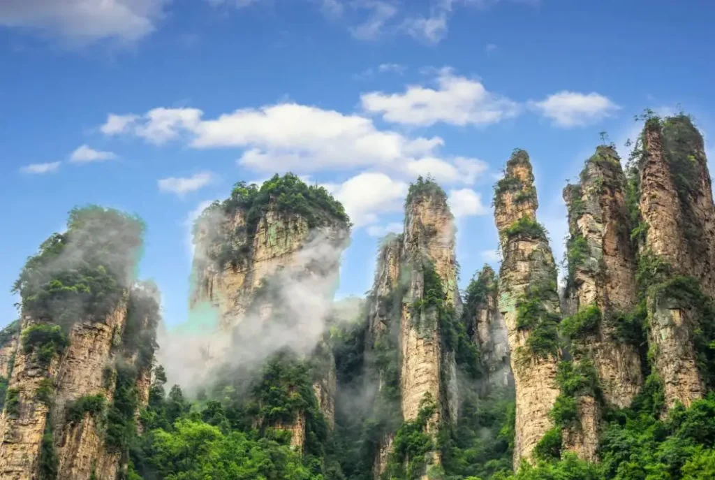 avatar mountain zhangjiajie: pilar batu pasir asli di Zhangjiajie National Forest Park dengan kabut dan langit biru