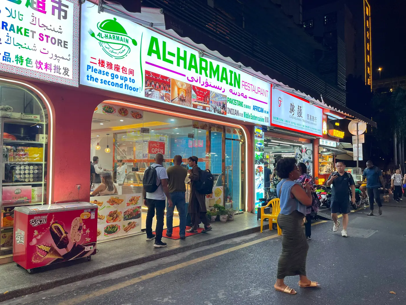 Restoran halal dengan papan berbahasa Arab dan Uyghur di jalan yang ramai pada malam hari di kawasan Muslim Xiaobei, Guangzhou