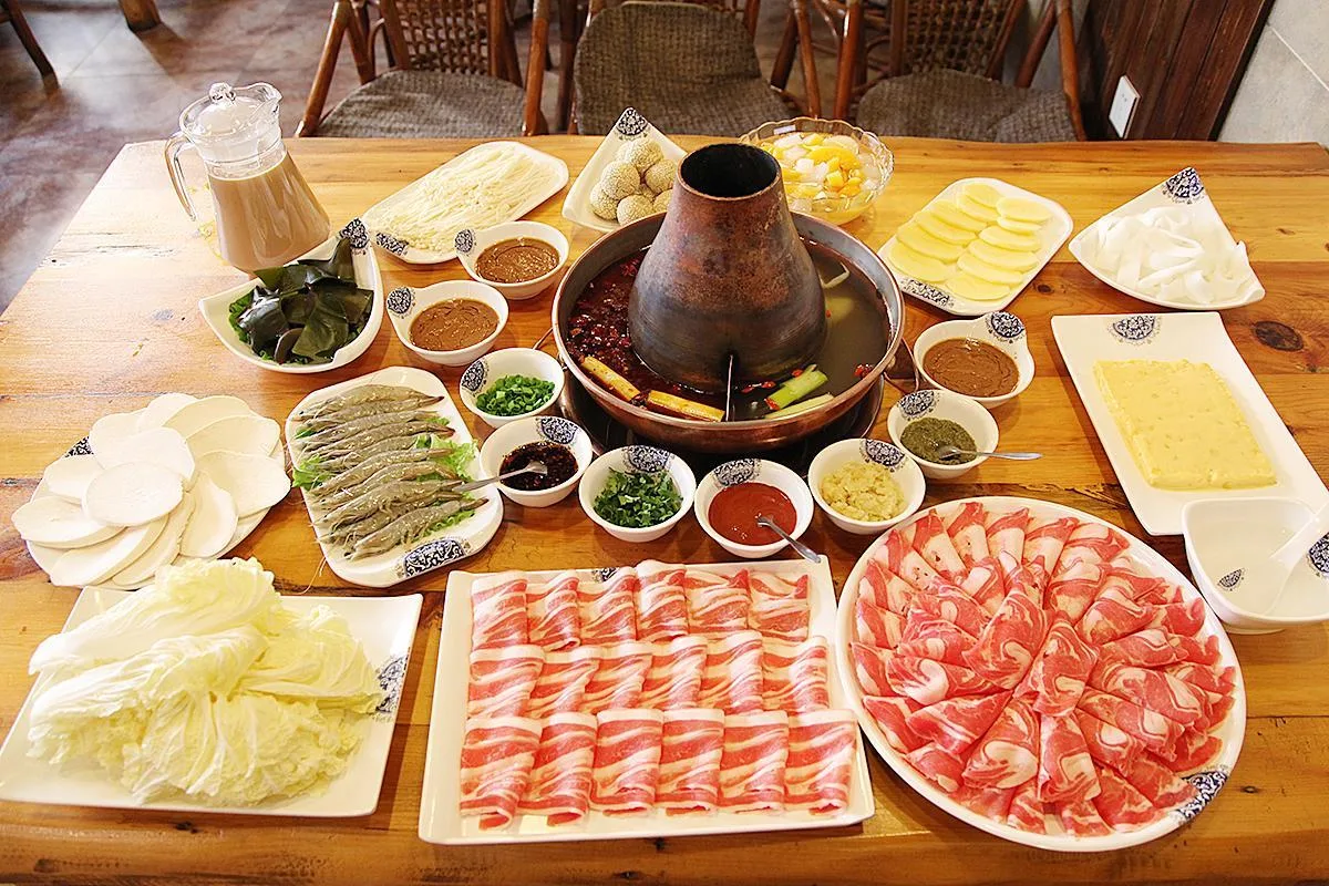 Meja hotpot halal dengan irisan daging sapi, kambing, dan sayuran segar di Chongqing