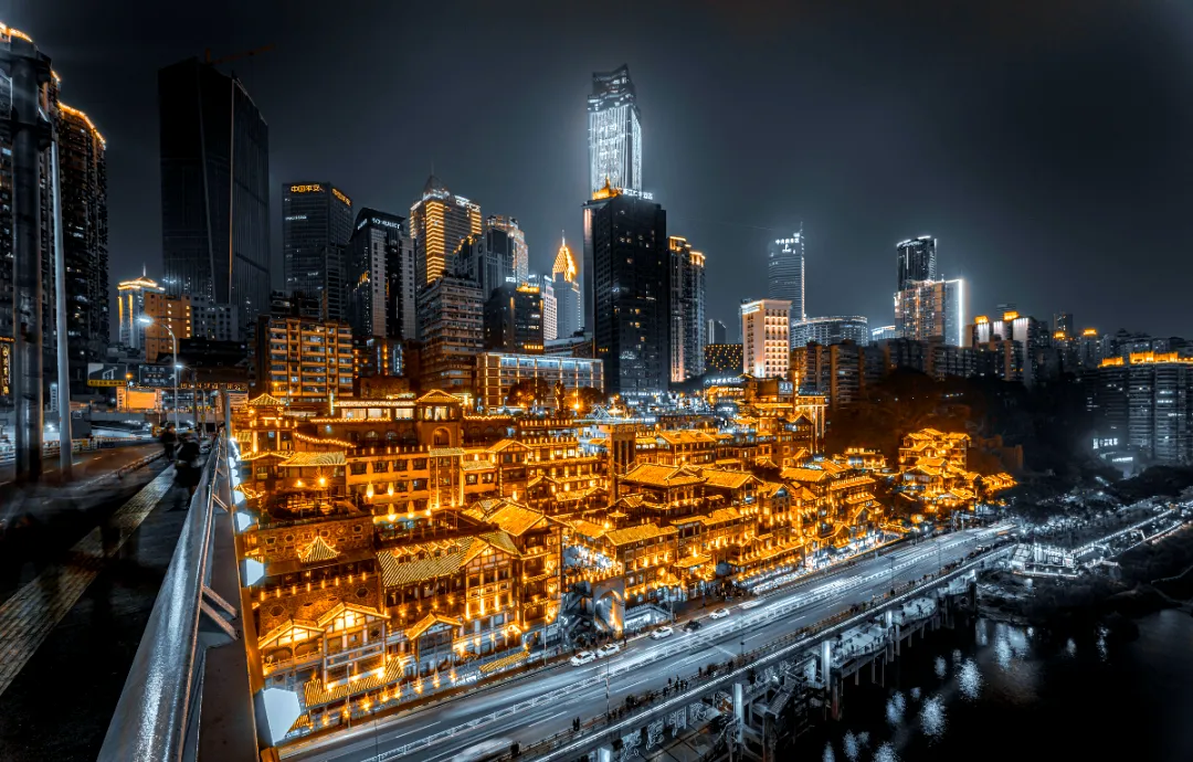 Kompleks rumah panggung tepi sungai Hongyadong bercahaya keemasan pada malam hari dilihat dari jalan layang, Chongqing