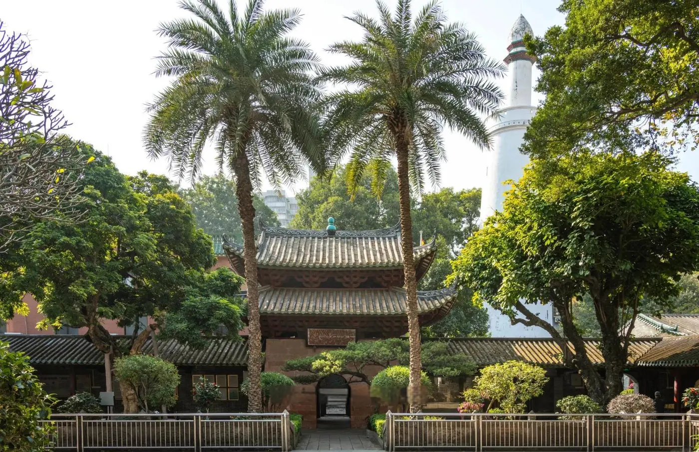 Halaman Masjid Huaisheng di Guangzhou dengan menara putihnya menjulang di balik pepohonan