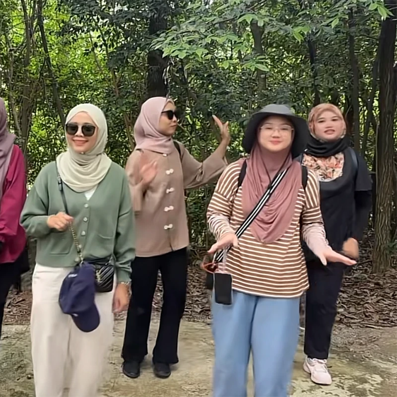 Rombongan wisatawan Muslim perempuan berjalan di jalur kayu hutan dalam tur Jiuzhaigou