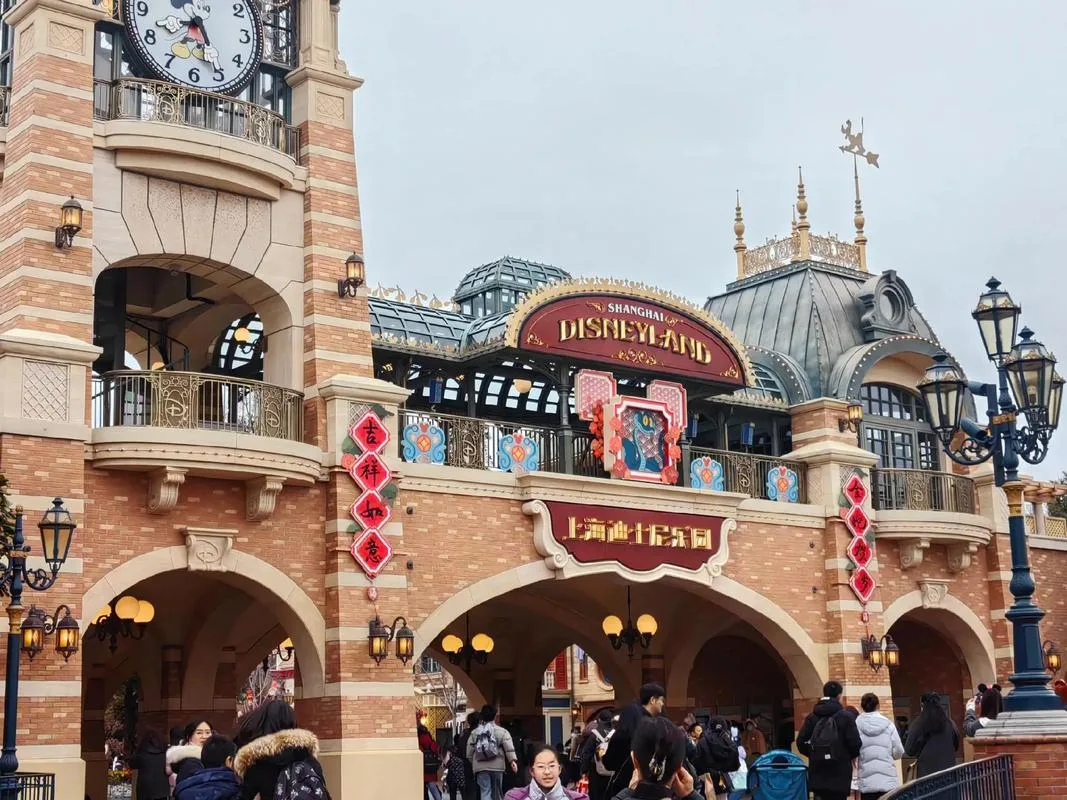 Gerbang masuk Shanghai Disneyland dengan menara jam taman hiburan dan para pengunjung