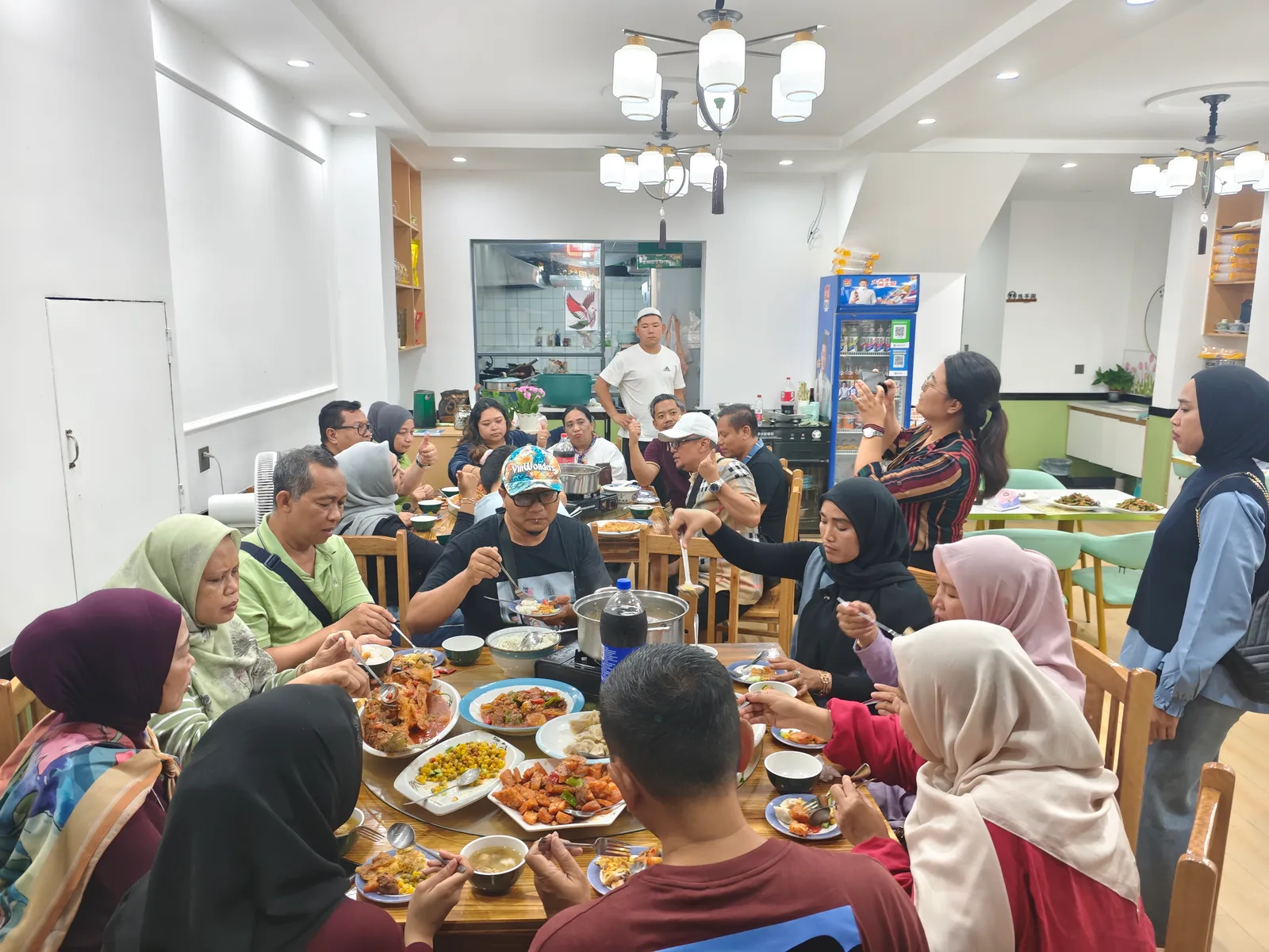Grup wisata Muslim yang lebih besar menikmati makan malam halal berkelompok di dua meja bundar di sebuah restoran halal di China