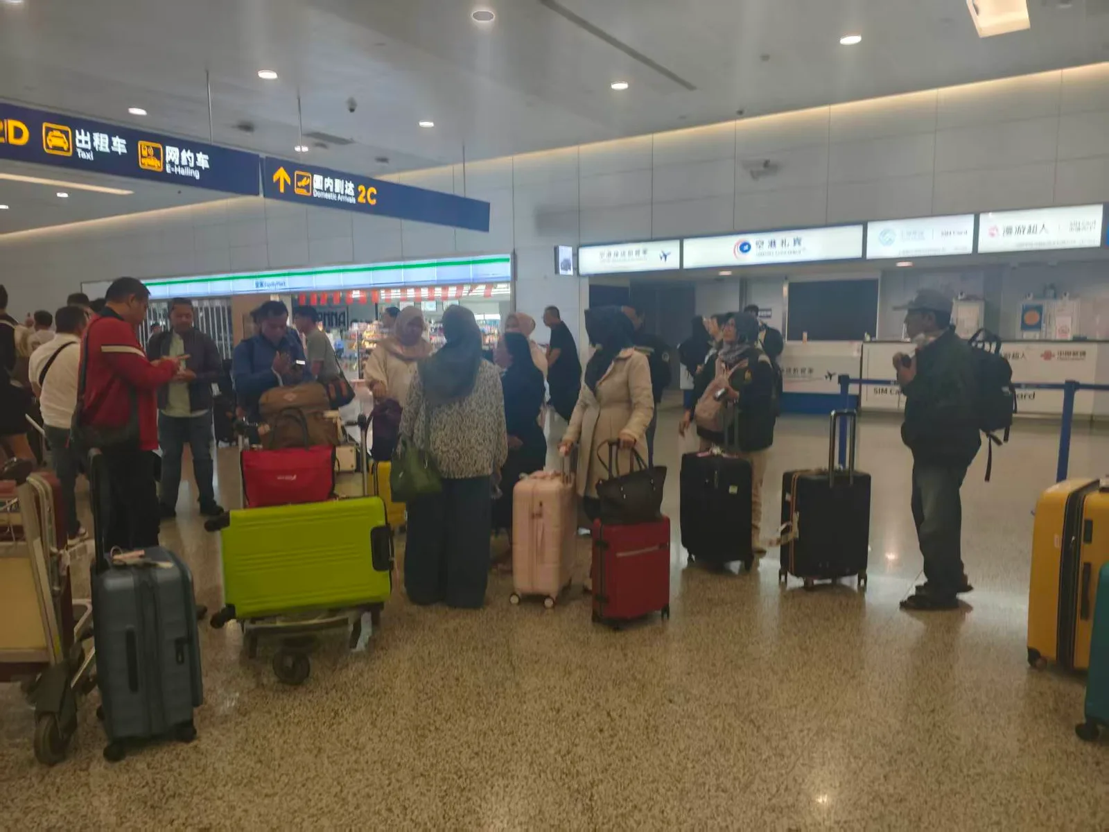 Rombongan pelancong Muslim dengan koper bertemu di aula kedatangan domestik sebuah bandara di Tiongkok