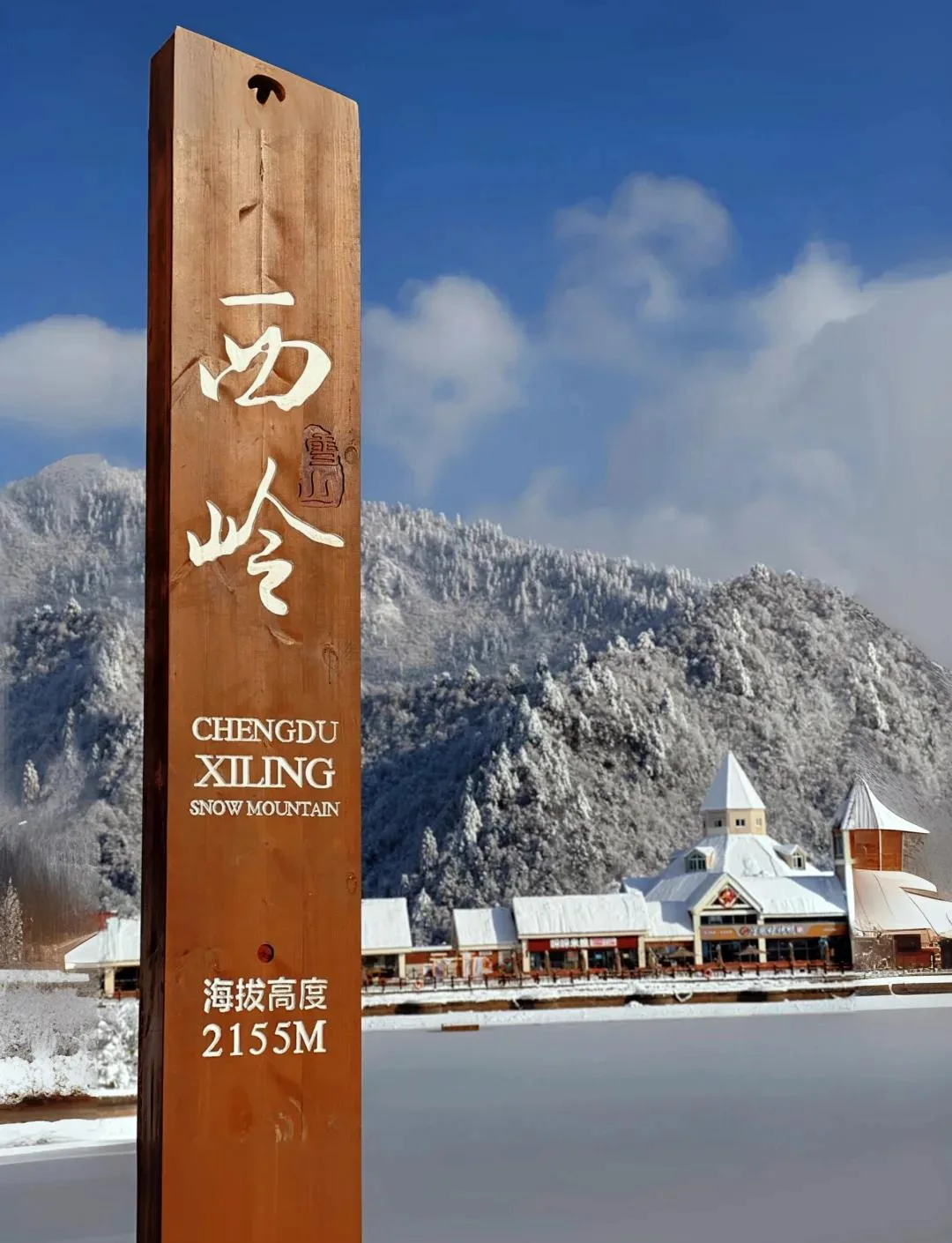 Penanda di Gunung Salju Xiling Chengdu yang menunjukkan ketinggian 2.155 m, dengan hutan bersalju di belakangnya